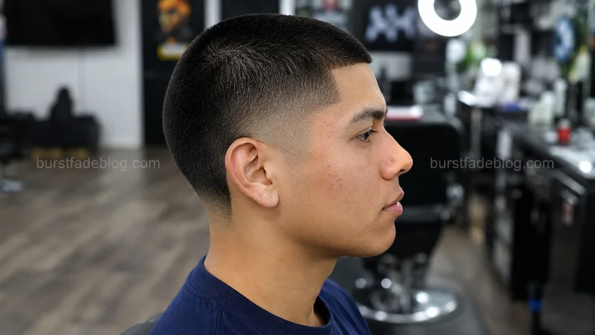 Low Burst Fade Buzz Cut haircut on a Latino male with a clean low fade around the ears and short buzzed top in a modern barbershop.